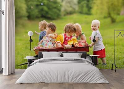 group of five toddlers riding in a red pull wagon on the farm Wall mural