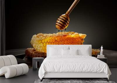 Honeycomb with honey and honey dipper on black background Wall mural