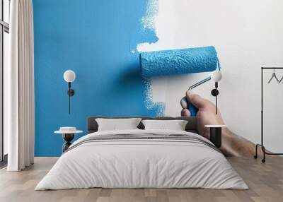 Male hand holding roller brush with blue paint on the wall Wall mural