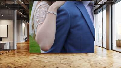 Bride in white wedding dress hugs groom from behind. European wedding. Details close-up. Wall mural