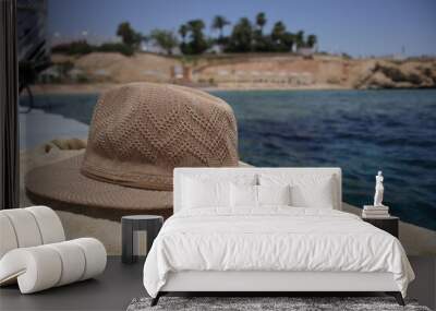 Summer hat and towel on the beach. Summer accessories for vacation on the background of the sea Wall mural