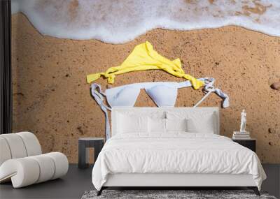 Flat lay picture of white and yellow bikini on sand -  vacation and nudist beach concept Wall mural