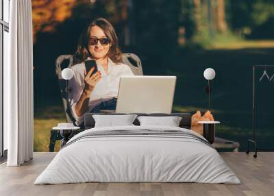 Young business woman is relaxing or working in the garden with smartphone and computer (laptop) - female freedom and independence concepts Wall mural