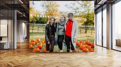 three teenage girls dance and laugh among mountain of pumpkins at the fall fair Wall mural