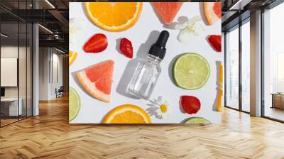 Top view of vitamin C dropper bottle, serum, cosmetic oil and slices of orange, lime, grapefruit on white background Wall mural