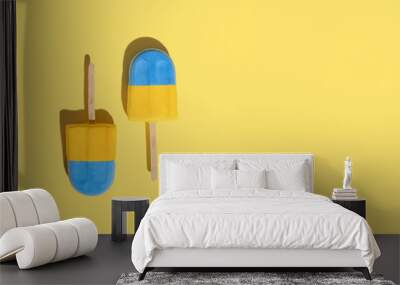 Two colored ice creams on a stick on a colored background. Hot summer weather concept. Refreshing summer food Wall mural