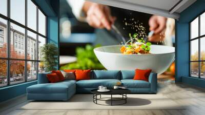 A chef adds herbs and microgreens to a vibrant salad in a bright, contemporary kitchen setting. Wall mural