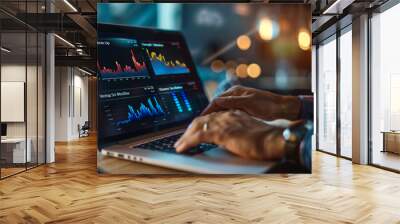 A person is typing on a laptop with a stock market graph on the screen. The person is focused on the screen and he is working on something related to finance or trading. Wall mural