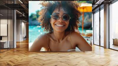 A young woman with curly hair enjoying a meal outdoors at a vibrant restaurant during a sunny day Wall mural