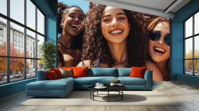 Energetic group of young women in blue athletic wear smiling together outdoors on a bright sunny day at the beach Wall mural