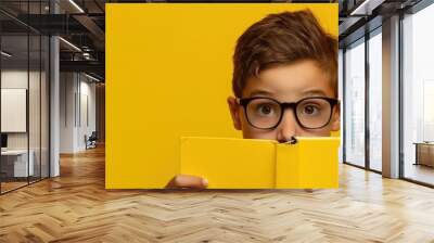 Smart boy with glasses reading a book on yellow background banner with space for your text Wall mural