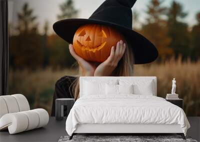 Image of happy young woman dressed in witch costume for Halloween holding pumpkin. Wall mural