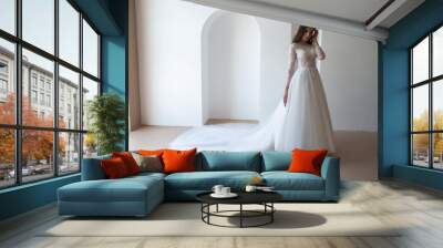 Full length portrait of young beautiful woman wearing white wedding dress. Elegant bride standing and posing Wall mural