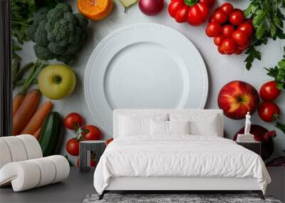 Fresh vegetables and fruits arranged around a clean white plate on a kitchen table, ready for meal preparation Wall mural