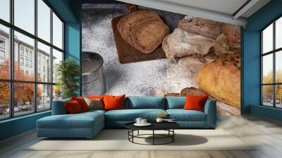 different types of sliced bread and a loaf on a wooden background . spilled flour. front view. copy  Wall mural