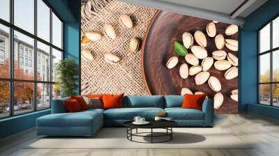 pistachios with leaves in a plate on a wooden background Wall mural