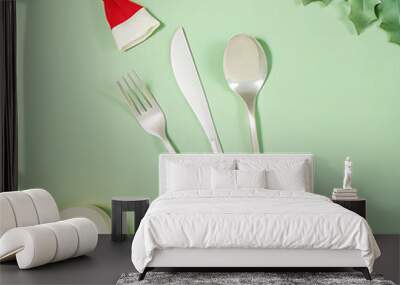 Silver knife fork and spoon with a Santa Claus red festive hat. Christmas meal background Wall mural