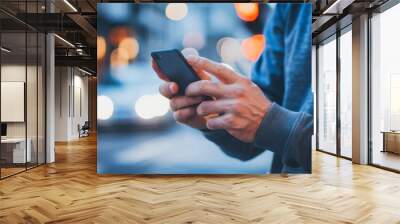 closeup of man hands on a phone browsing on social media while standing outdoors in the city street. guy reading an article or blog on a website with a smartphone in an urban town road. Wall mural