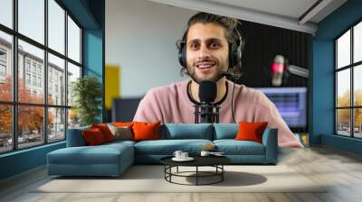 Portrait of a young man talking on the microphone at the radio station Wall mural