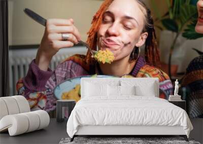 This is Delicious! Woman eating a home made vegan dish. Her and her friends have cooked creole aubergines and quinoa with sweet potatoes, peppers and avocado puree. She has her eyes closed and is enjo Wall mural