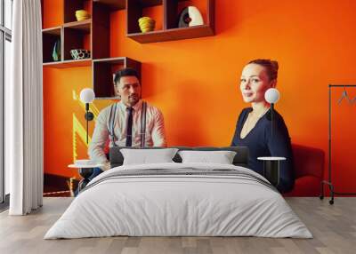 positive young man in official outfit and beautiful business woman sitting at coffee table talking a Wall mural