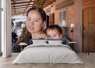 Asian woman carrying her baby girl on back Wall mural