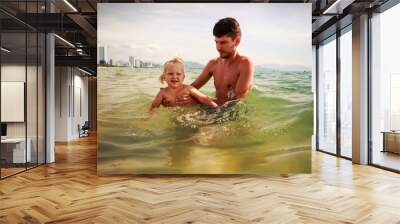 father teaches little daughter to swim in shallow sea water Wall mural