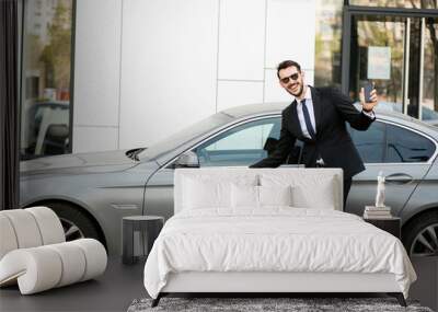 successful and handsome man in suit outside with his expensive car Wall mural