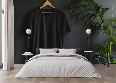 A black tshirt hanging on a wooden hanger over a black wall background with a plant, a mockup template for design presentation  in a minimalist style with copy space. Wall mural