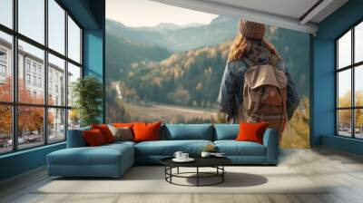 candid shot from the back of a young woman traveler in vintage style with a tourist backpack looking at the stunning view of the mountains and forest. travel and hiking concept. copy space. Wall mural