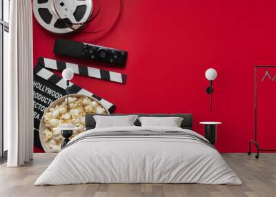 flat lay composition with popcorn, movie clapperboard, film reel and tv remote control on red background. copy space. place for text. home movie night concept Wall mural