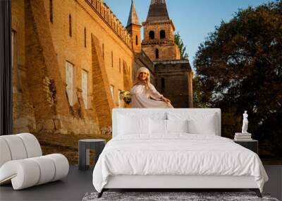 blonde girl in a white dress on nature near architectural monuments in the open air Wall mural