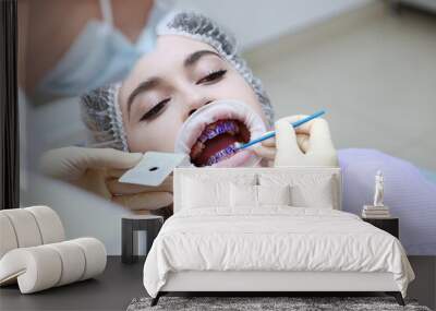 Professional hygiene of the oral cavity. The dentist applies a purple gel to the patient's teeth before professional dental cleaning. Prevention of caries and gum diseases. Hands in protective gloves. Wall mural