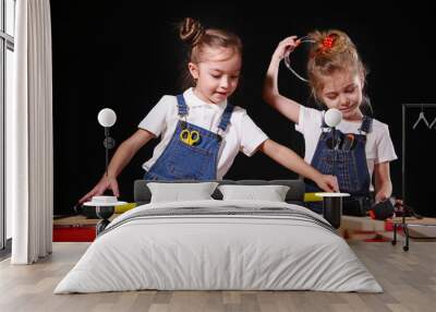 Two little girls in the carpenter's shop playing in adult profession. The concept of a happy childhood. Education for kids. Wall mural