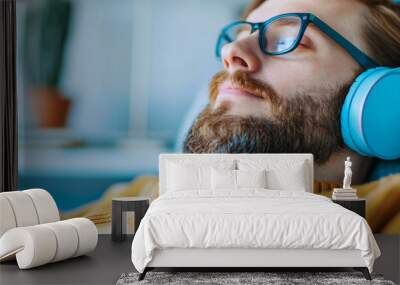 Man relaxing with headphones and blue sweater indoors Wall mural