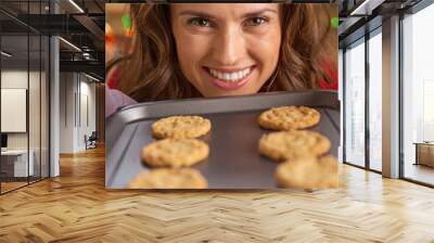 Happy young housewife showing pan with christmas cookies Wall mural