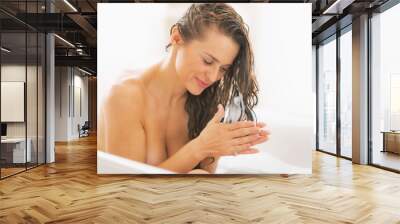 Happy young woman applying hair conditioner in bathtub Wall mural