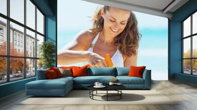 Happy young woman on beach applying sun screen creme Wall mural