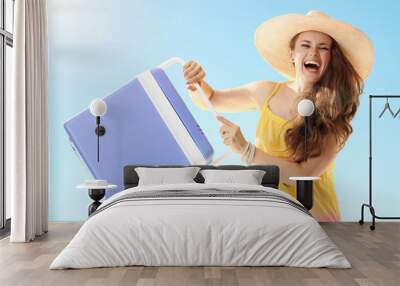 happy young woman with blue plastic cooler box against blue sky Wall mural