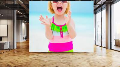 Portrait of cheerful baby girl in sunglasses on beach Wall mural