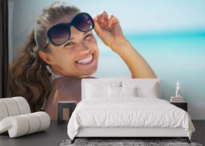 Portrait of happy young woman in sunglasses on beach Wall mural