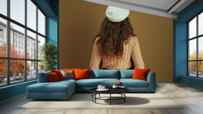 Seen from behind woman in sweater isolated on beige Wall mural