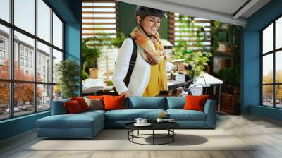 smiling elegant business woman in bike helmet in eco office Wall mural