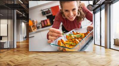 Smiling elegant woman preparing roasted pumpkin dish Wall mural