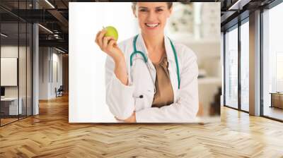 Smiling medical doctor woman with apple Wall mural