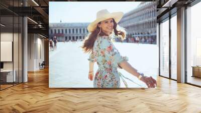 smiling solo tourist woman in floral dress having walking tour Wall mural