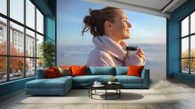 smiling stylish woman in cosy sweater at beach in evening Wall mural