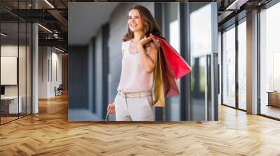 Smiling woman with three shopping bags looking into distance Wall mural