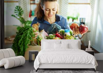 smiling young housewife with food box in kitchen Wall mural