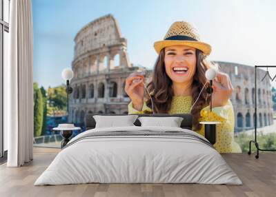 Woman standing near Colosseum in Rome removing earbuds Wall mural